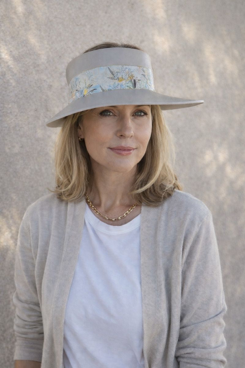 Woman wearing a wide-brimmed hat with floral band against a neutral background