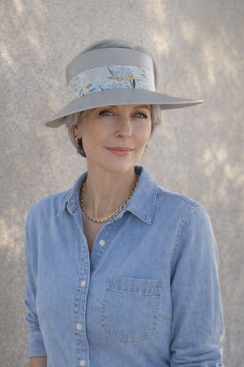 Woman wearing a wide-brimmed hat with a floral band against a neutral background