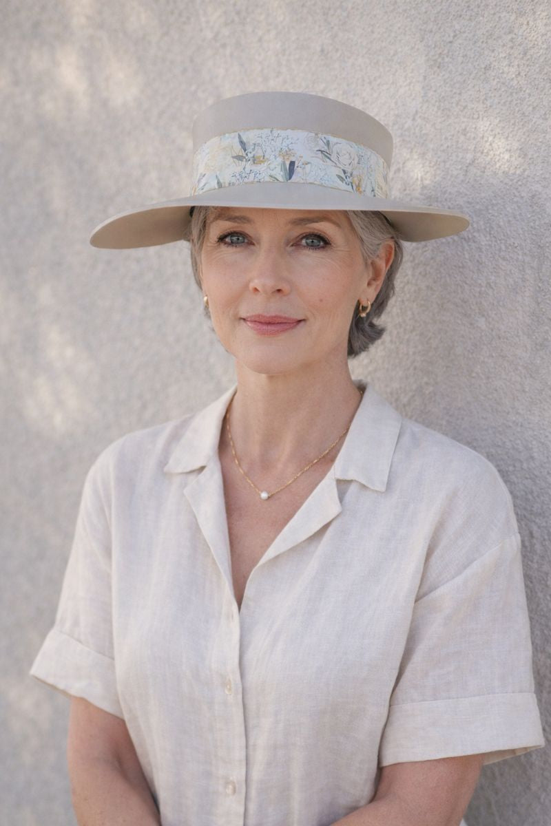 Woman wearing a wide-brimmed hat with a floral band against a light background