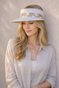 Woman wearing a white visor against a beige wall