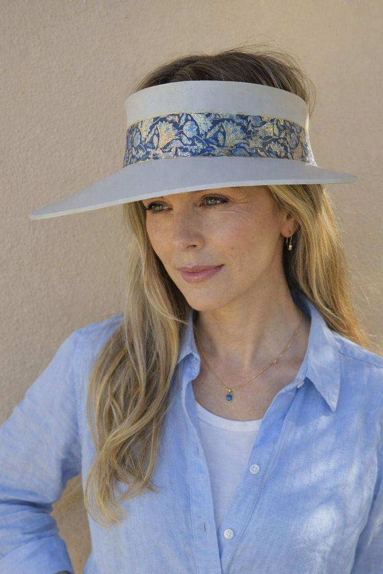Woman wearing a light blue visor with floral pattern against a beige background