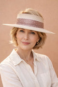 Woman wearing a wide-brimmed hat with a decorative band against a beige background