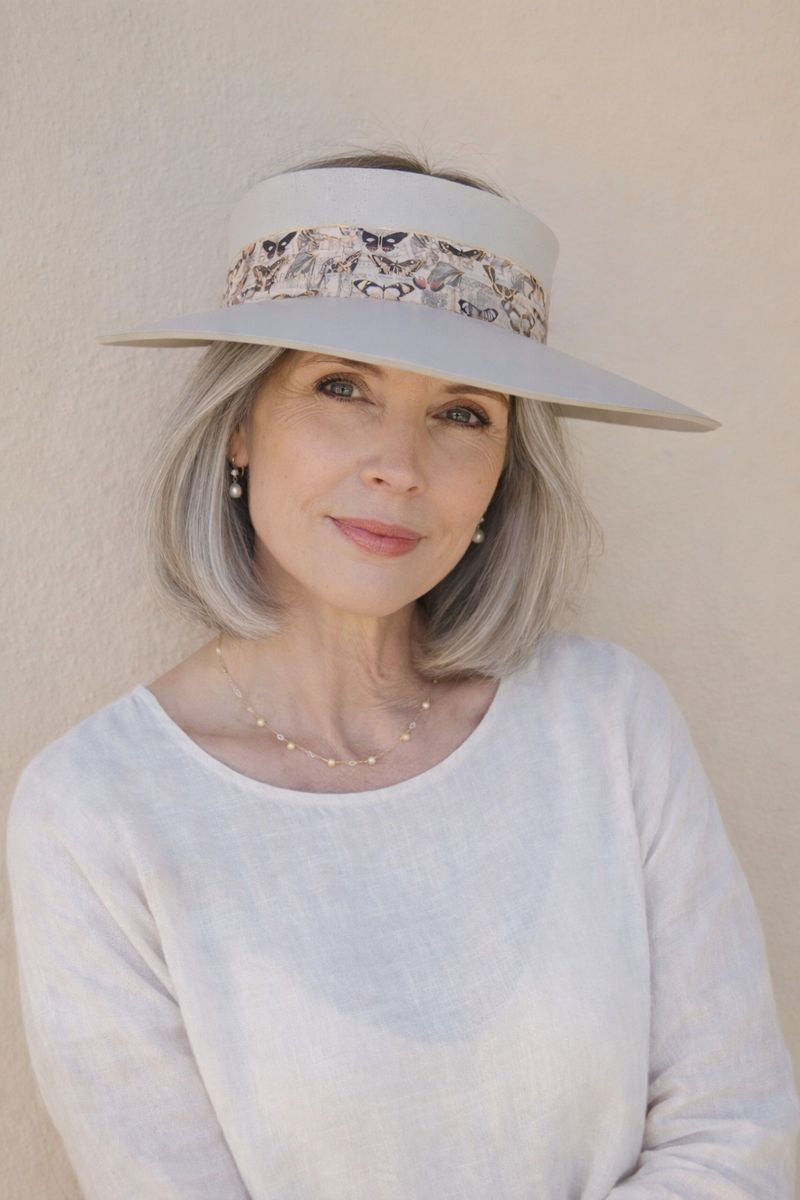 Woman wearing a wide-brimmed hat with decorative band against a plain background