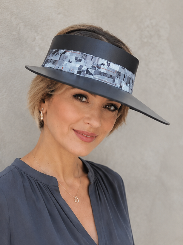 Woman wearing a wide-brimmed hat with a patterned band against a plain background