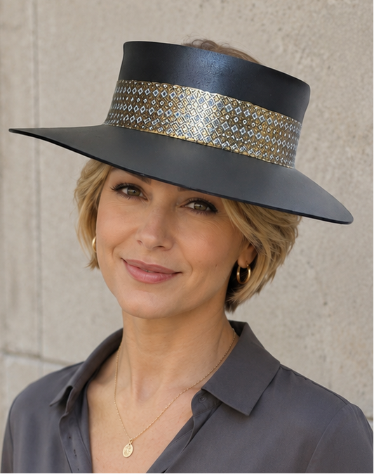 Woman wearing a wide-brimmed hat with a decorative band against a concrete wall.