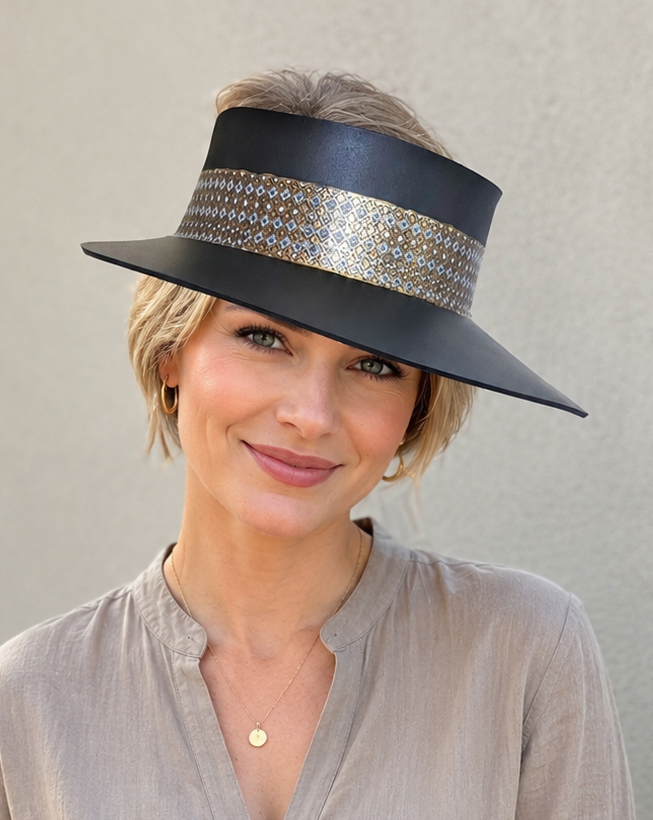 Woman wearing a black hat with a decorative band against a plain background