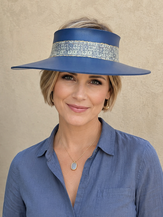 Woman wearing a blue sun visor hat and matching shirt against a beige background