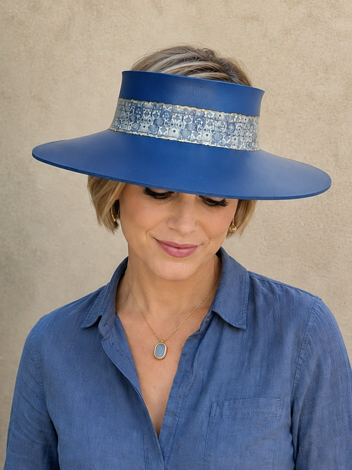 Woman wearing a blue visor hat and matching shirt against a beige background