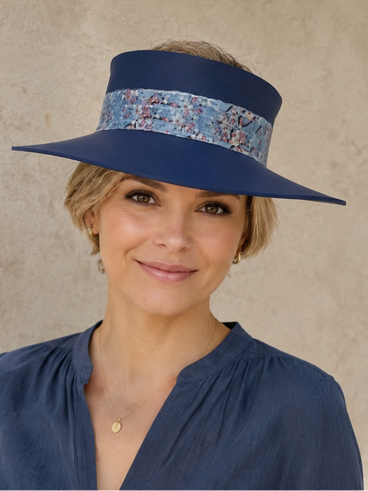 Woman wearing a blue visor hat with a floral band against a beige wall