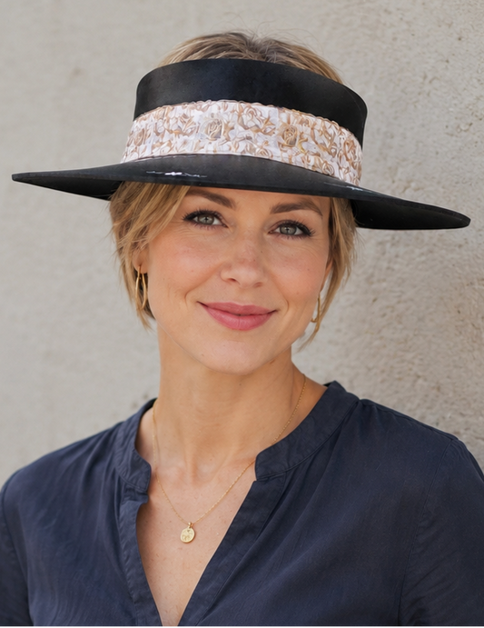 Woman wearing a wide-brimmed hat with a floral band against a plain background
