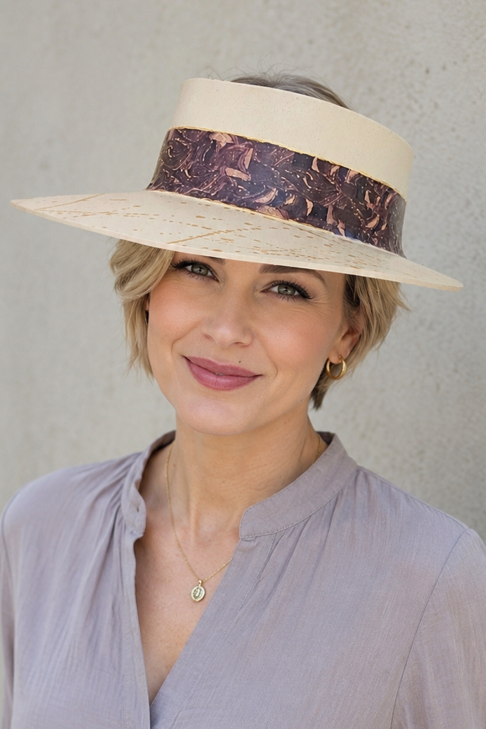 Woman wearing a wide-brimmed hat with a decorative band against a plain background
