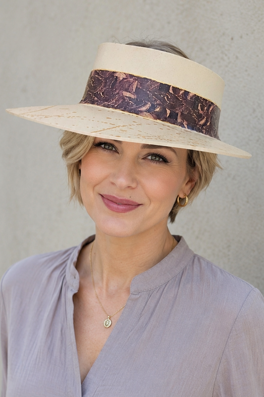 Woman wearing a wide-brimmed hat with a decorative band against a plain background