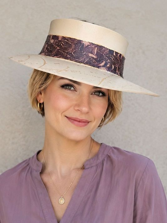 Woman wearing a wide-brimmed hat with a decorative band against a plain background