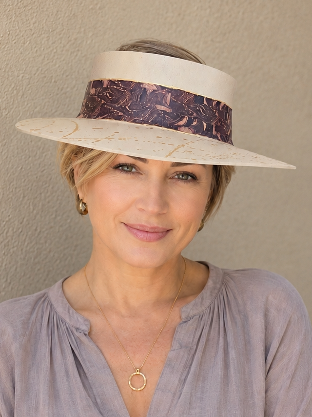 Woman wearing a wide-brimmed hat with a floral band against a plain background