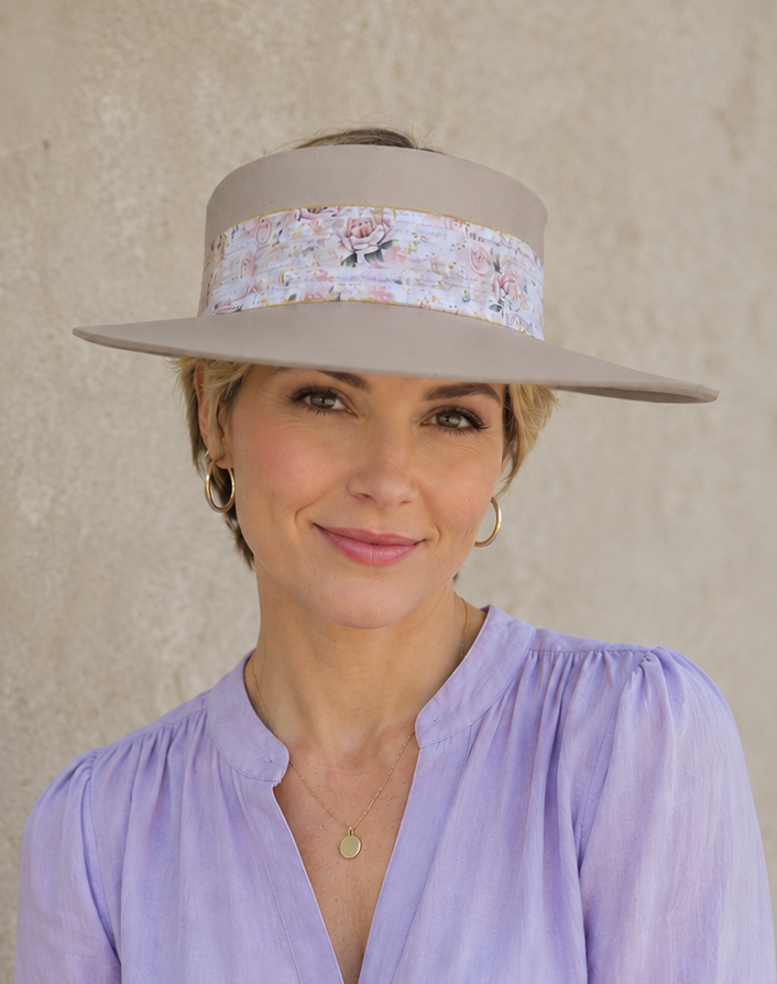 Woman wearing a wide-brimmed hat with a floral band against a plain background