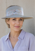Woman wearing a light purple shirt and a wide-brimmed hat against a neutral background