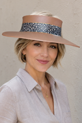 Woman wearing a wide-brimmed hat with a decorative band against a plain background