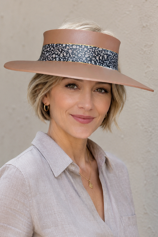 Woman wearing a wide-brimmed hat with a decorative band against a plain background