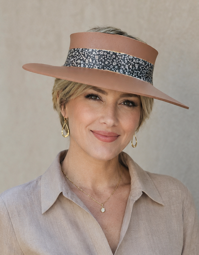 Woman wearing a wide-brimmed hat with a patterned band against a plain background