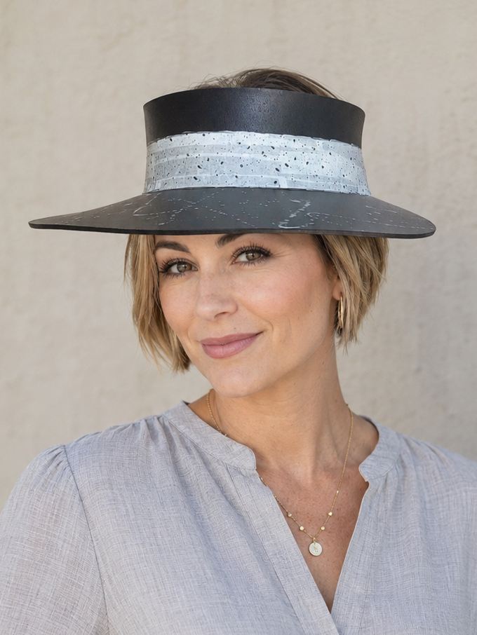 Woman wearing a wide-brimmed hat with a decorative band against a neutral background