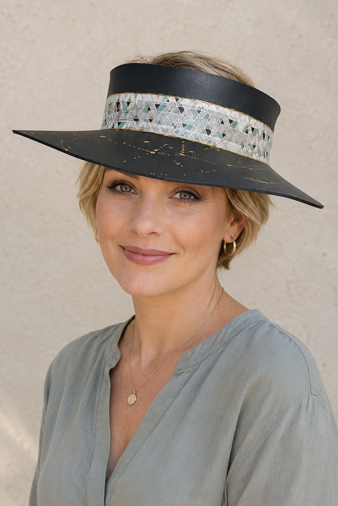 Woman wearing a wide-brimmed hat with decorative band against a beige wall