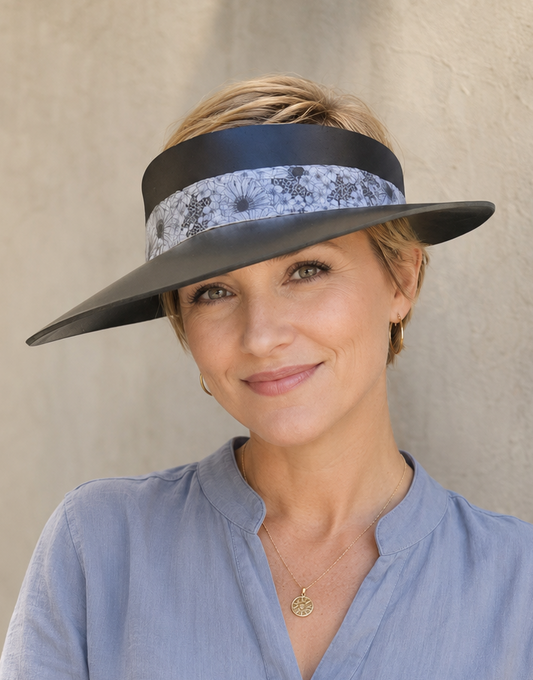 Woman wearing a wide-brimmed hat with a decorative band against a neutral background