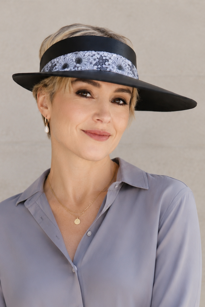 Woman wearing a wide-brimmed hat with a decorative band against a neutral background