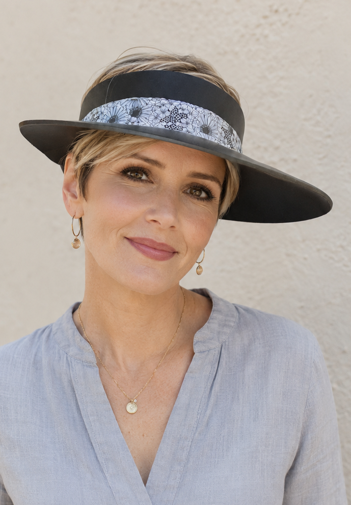 Woman wearing a wide-brimmed hat with a patterned band against a plain background