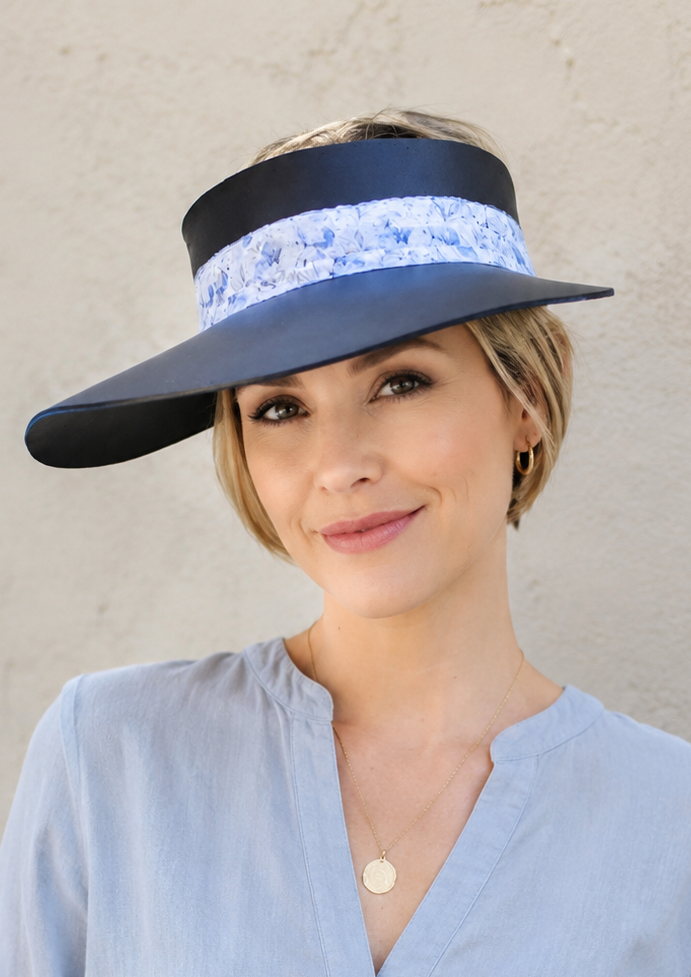 Woman wearing a wide-brimmed hat with a decorative band against a plain background