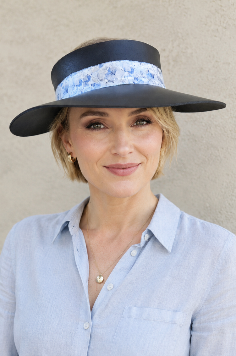Woman wearing a wide-brimmed hat with floral band against a beige background