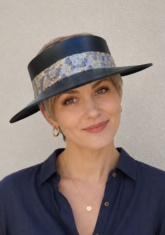 Woman wearing a navy blue hat with floral band against a plain background