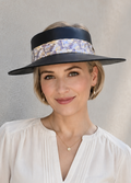 Woman wearing a wide-brimmed hat with a decorative band against a neutral background