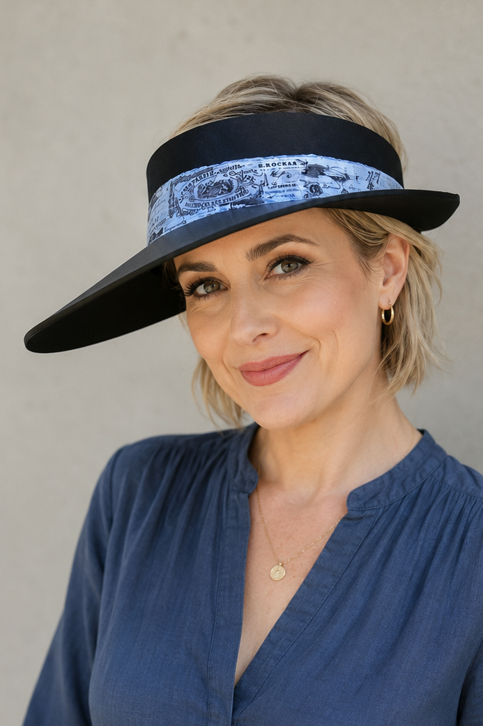 Woman wearing a blue blouse and black visor against a plain background