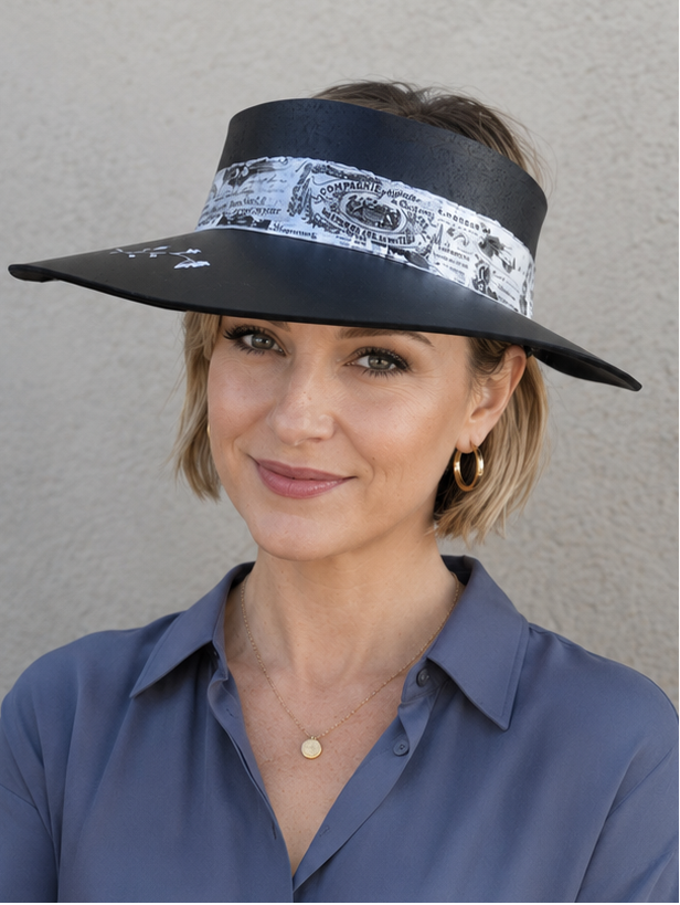 Woman wearing a wide-brimmed hat with a decorative band against a plain background