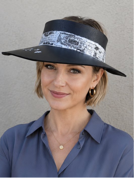 Woman wearing a wide-brimmed hat with a decorative band against a plain background