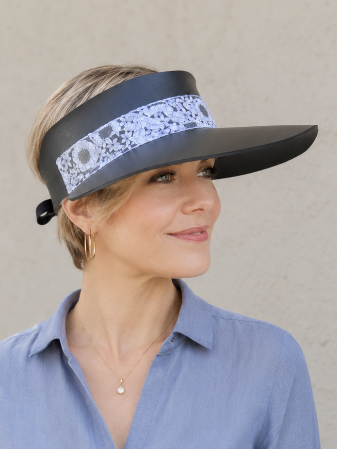 Woman wearing a wide-brimmed visor with floral band against a neutral background