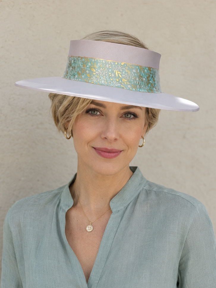Woman wearing a wide-brimmed hat with a decorative band against a plain background