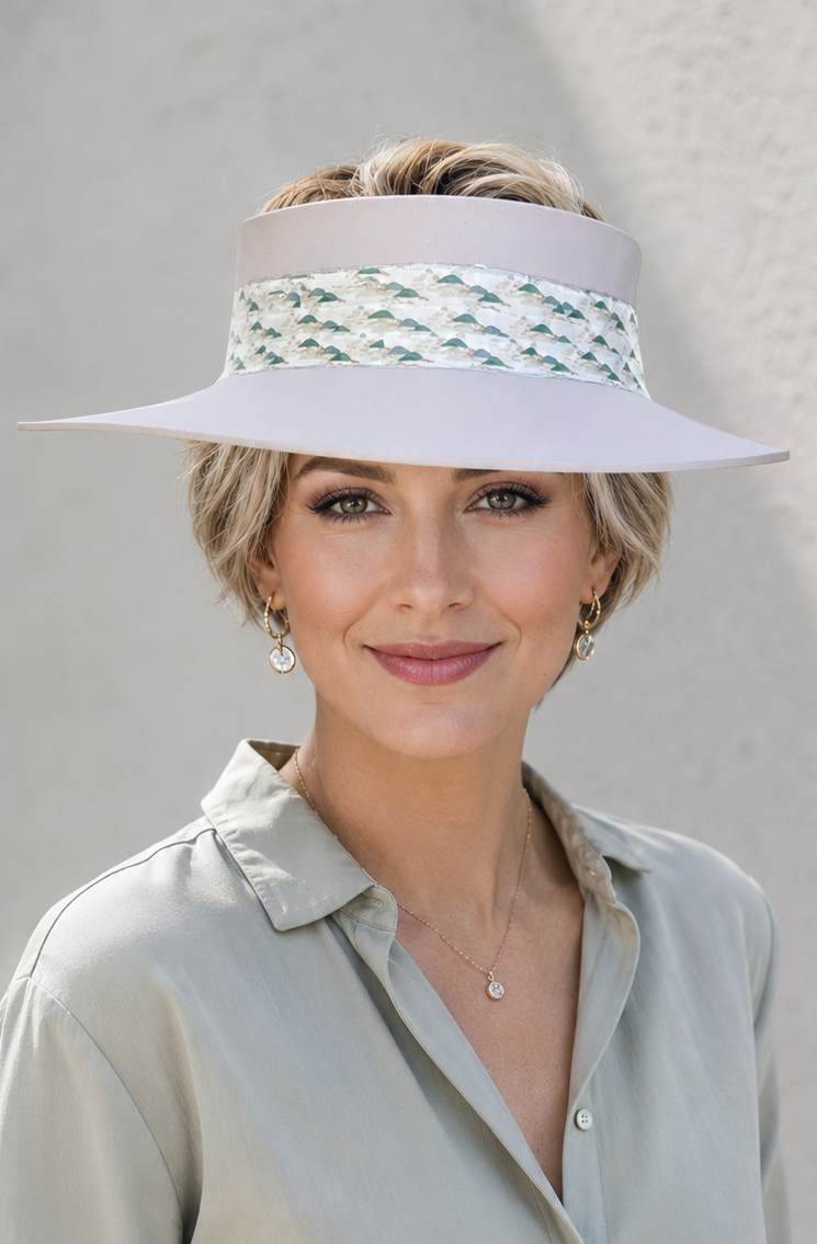 Woman wearing a white visor with decorative band against a plain background