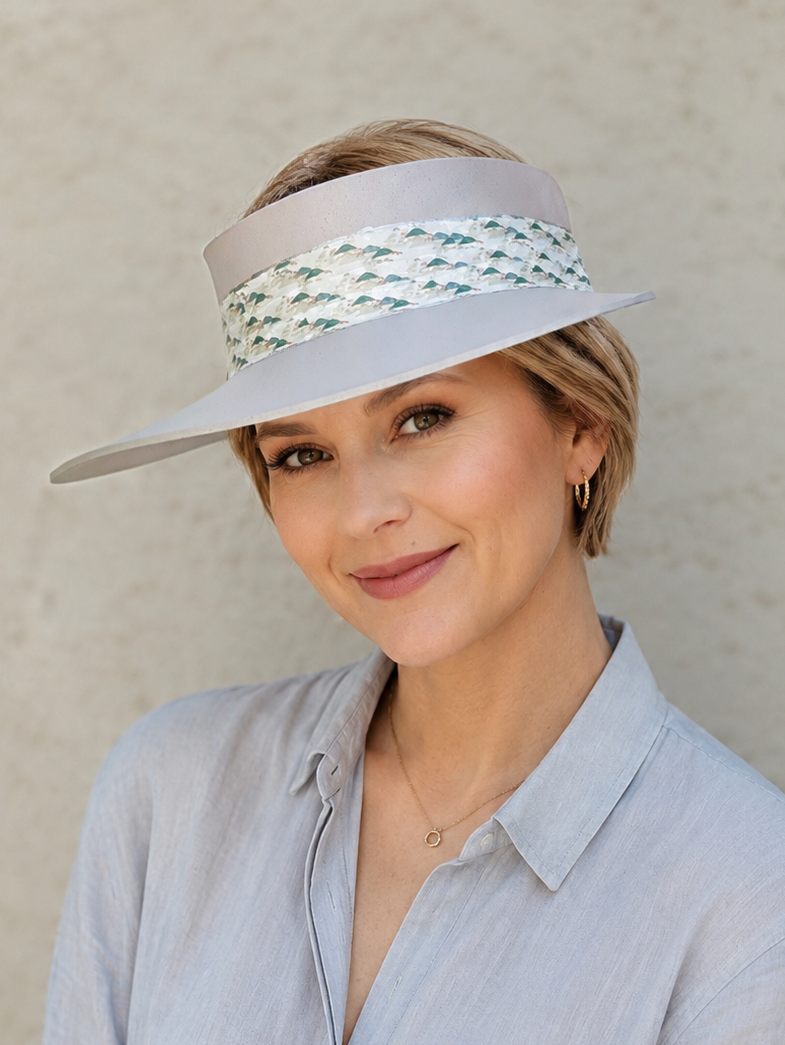 Woman wearing a wide-brimmed hat with a decorative band against a plain background