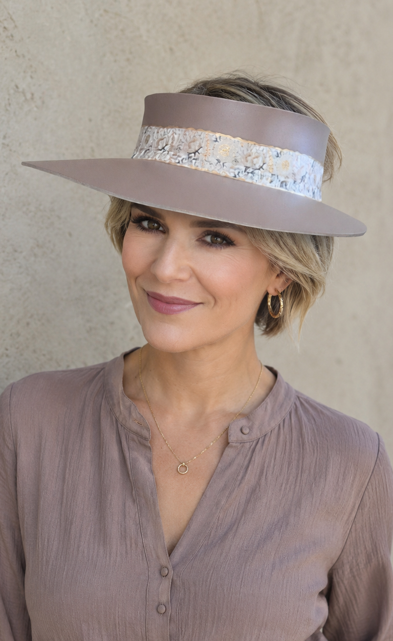 Woman wearing a wide-brimmed hat against a beige wall