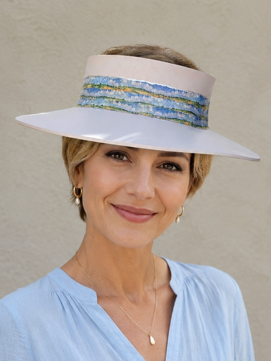Woman wearing a wide-brimmed hat with a colorful band against a plain background