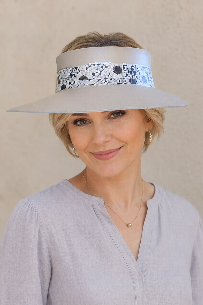 Woman wearing a wide-brimmed hat with a decorative band against a beige wall
