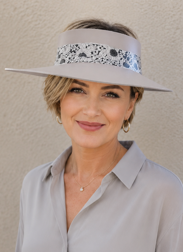 Woman wearing a light gray blouse and visor against a beige background