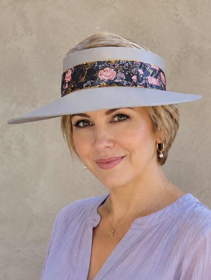 Woman wearing a wide-brimmed hat with a floral band against a beige background