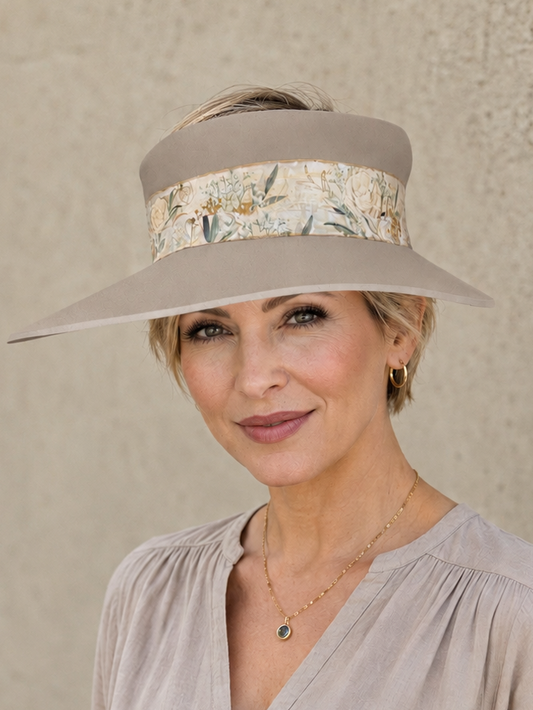 Woman wearing a wide-brimmed hat with floral band against a neutral background