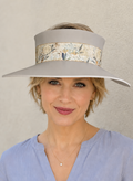 Woman wearing a wide-brimmed hat with a floral band against a plain background
