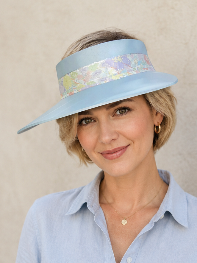 Woman wearing a light blue visor and shirt against a beige background