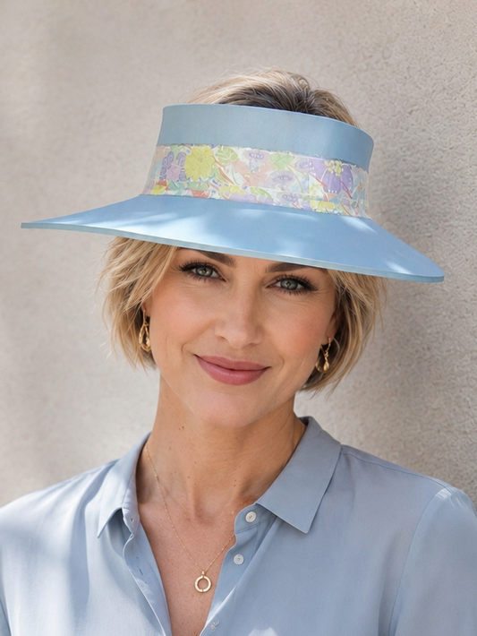 Woman wearing a light blue visor hat with floral band against a beige background