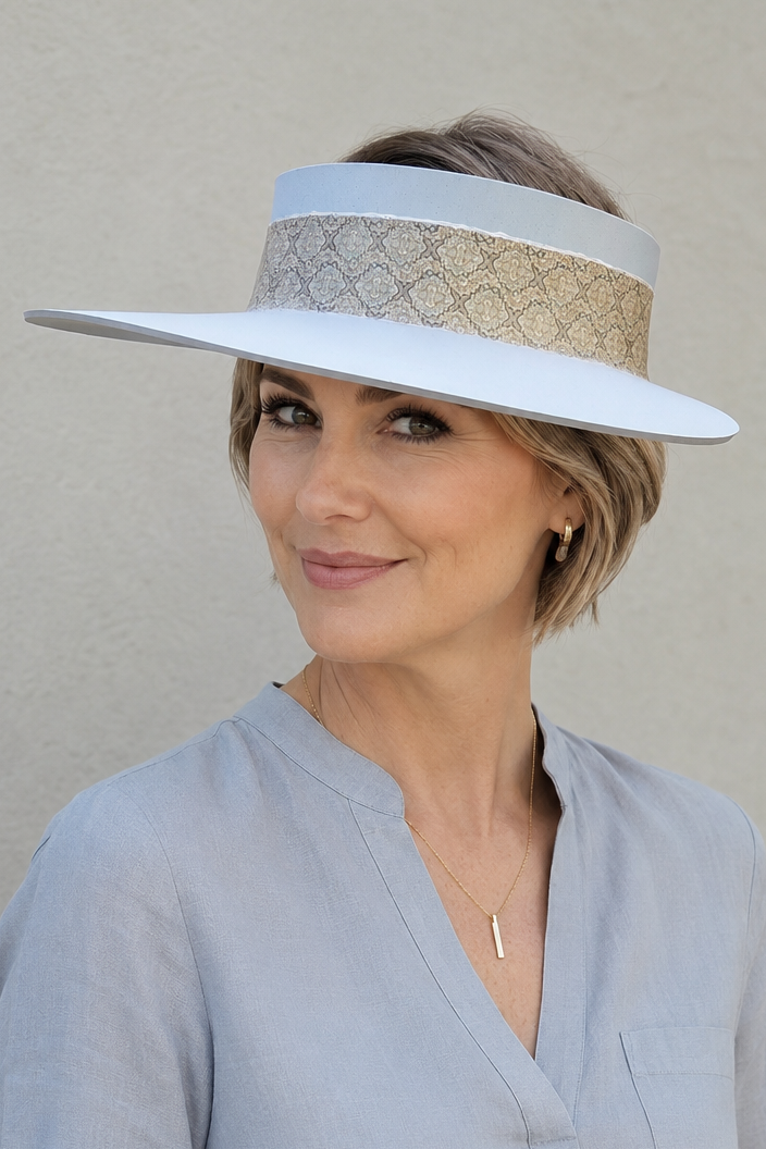 Woman wearing a light blue visor and light gray blouse against a beige background