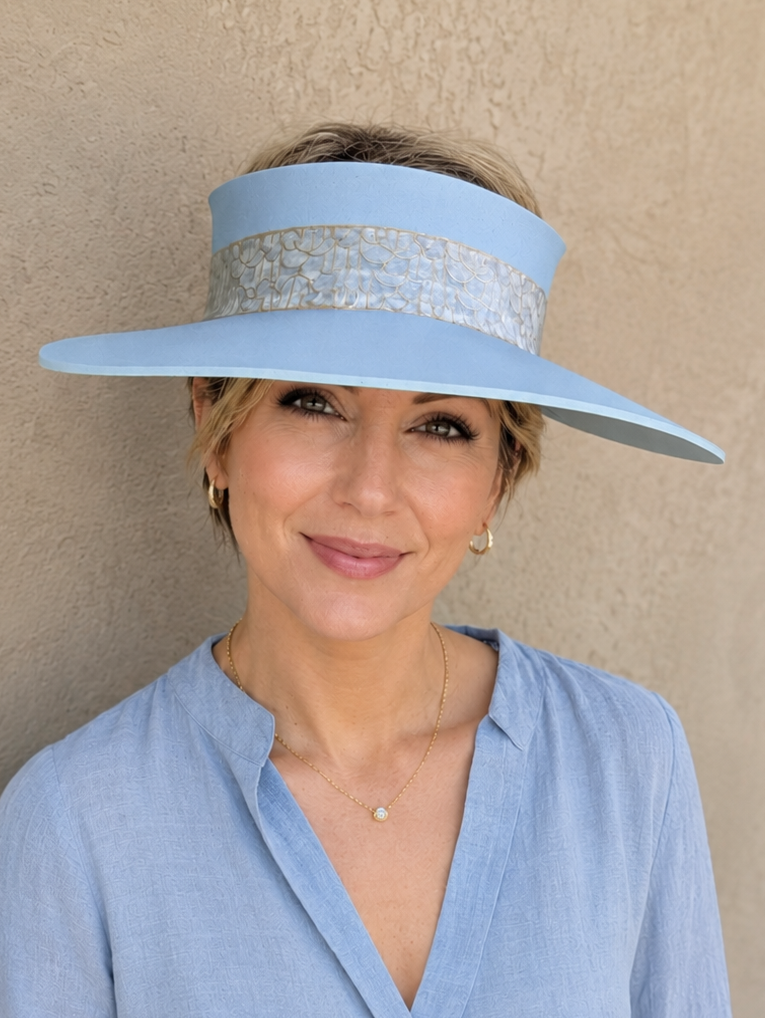 Woman wearing a light blue visor and matching blouse against a beige wall